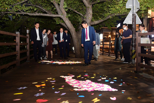 부산 동래구 온천천 카페거리 경관조명 시연회에서 형형색색 조명 위를 거닐어 보는 장준용 동래구청장(가운데). [사진=동래구]