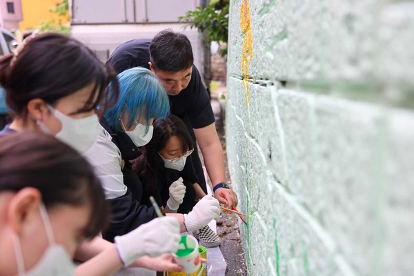 경남정보대학교 시각디자인학과 학생들이 부산 사상구 괘내마을의 노후 옹벽에 벽화글 그리는 봉사를 하고 있다. [사진=경남정보대]